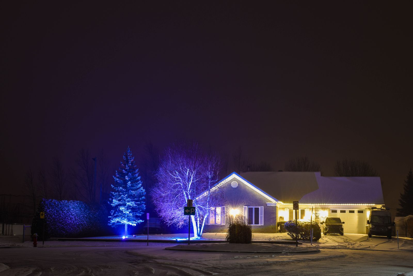 A suburban home at night, professionally lit for Christmas